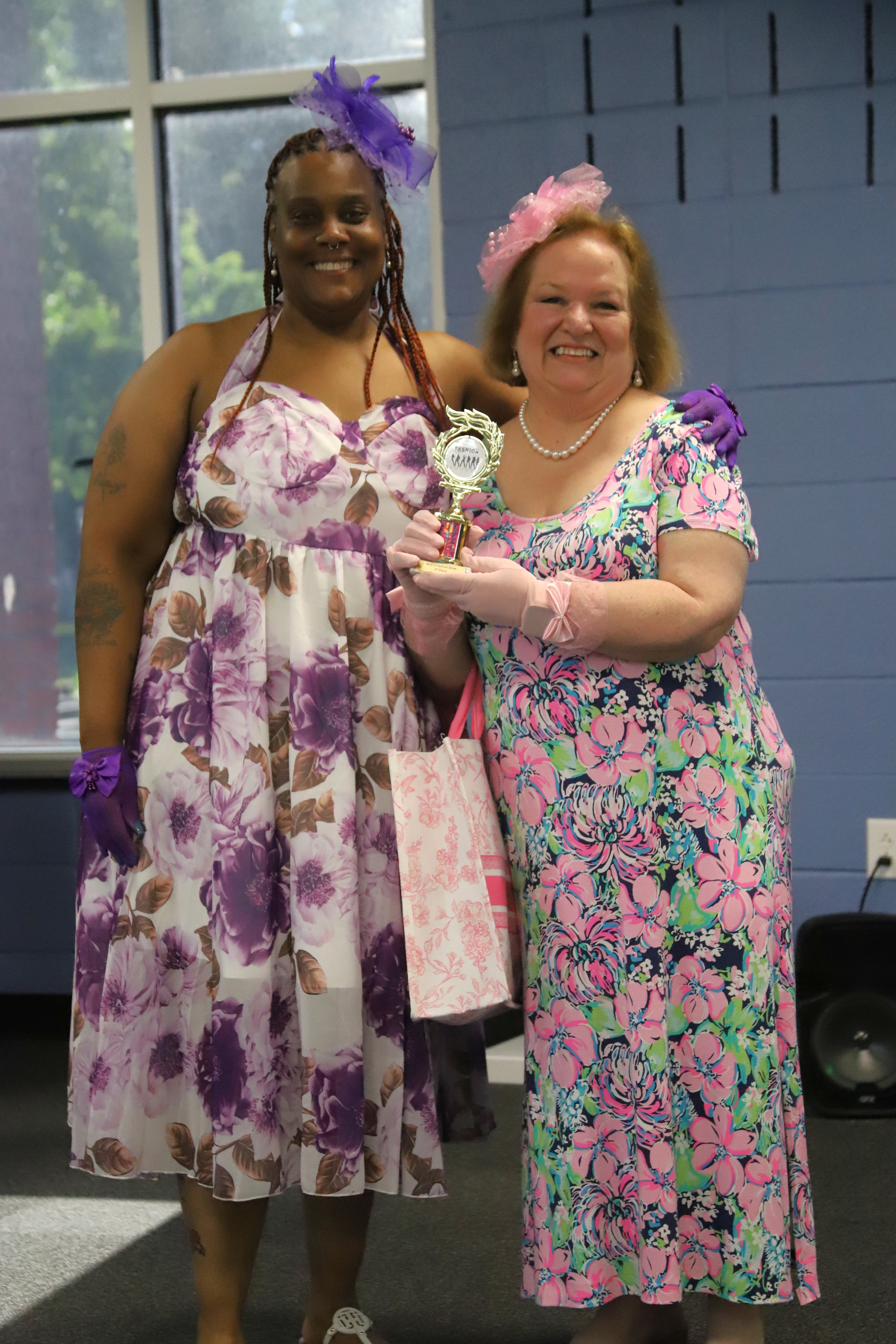 Two fashion show winners, including Joan Watts, holding trophies at the ladies' tea event